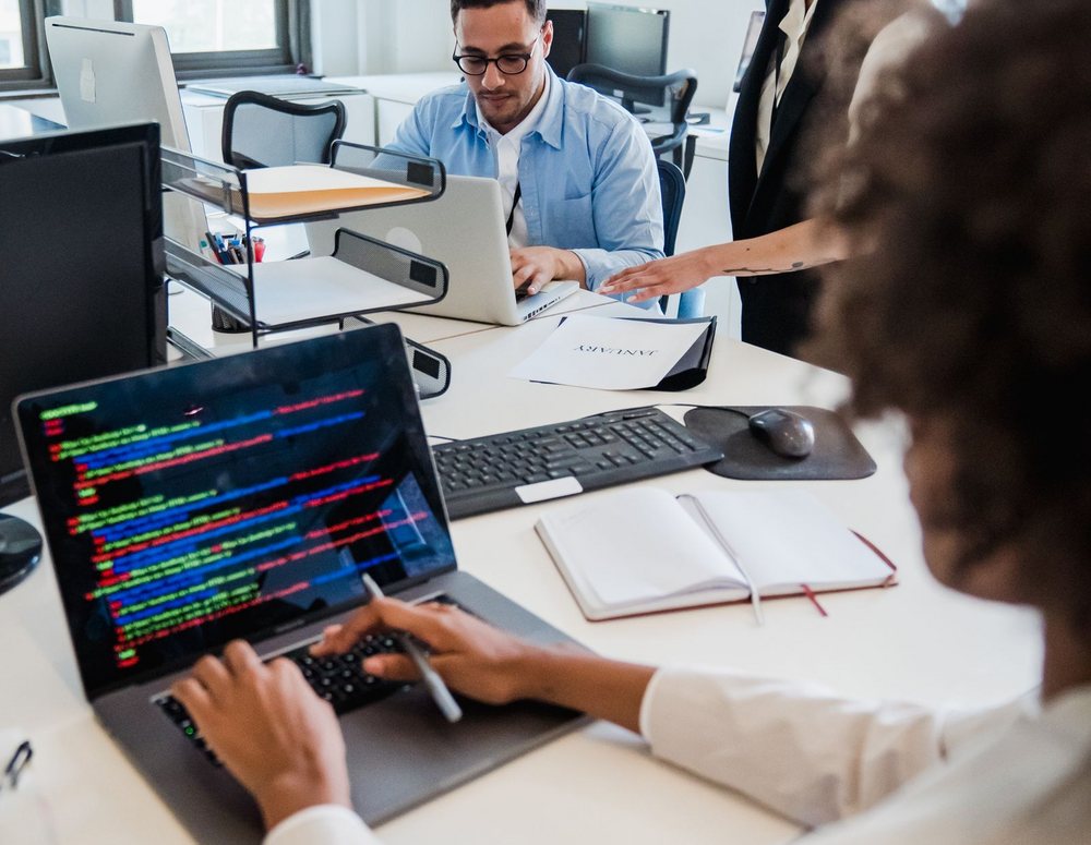 Consultants working through code and migration notes together at a shared desk